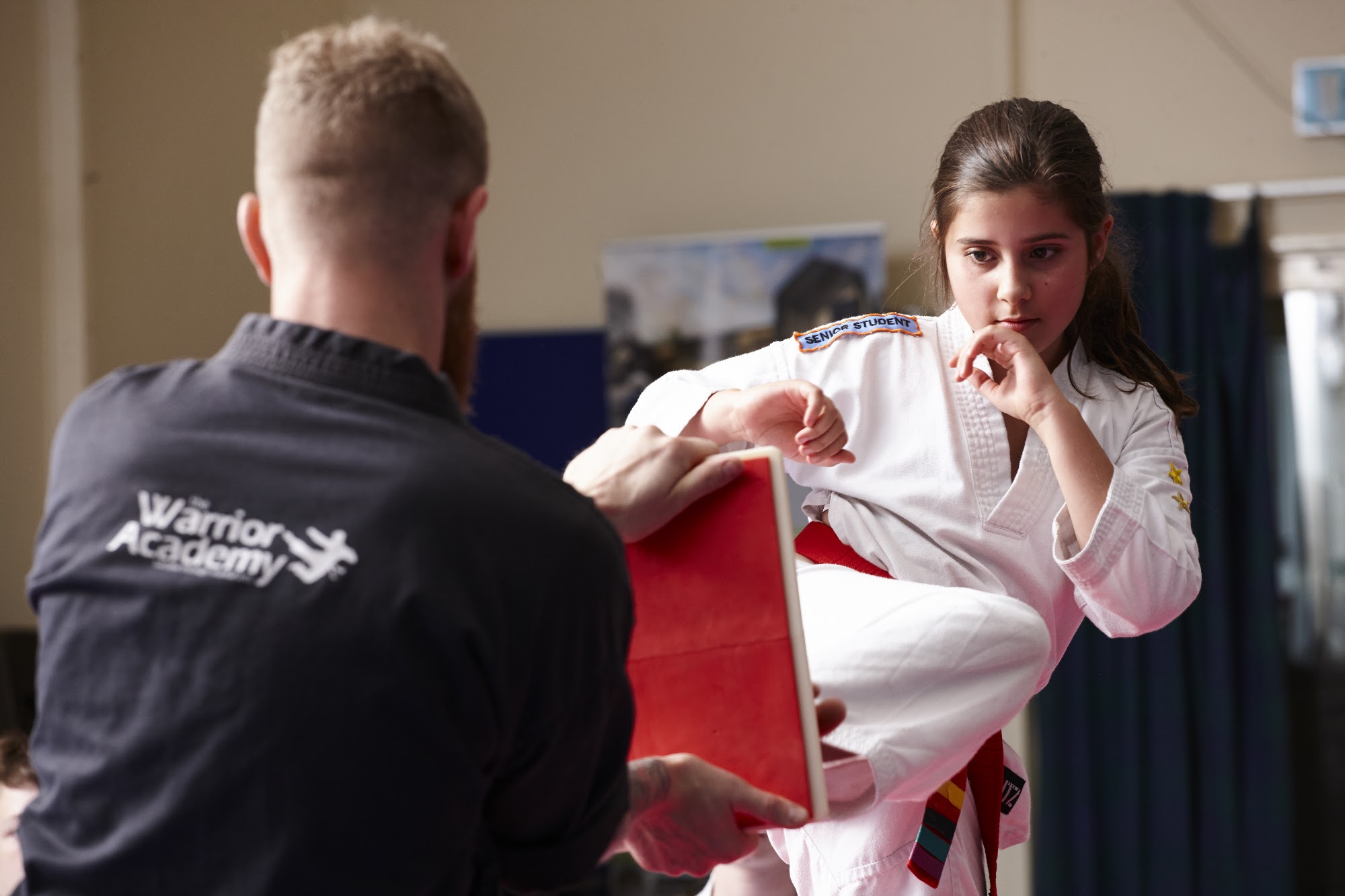 A student striking a focus pad held by her instructor